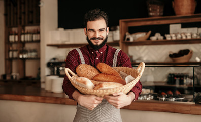 Cheerful baker with basket full of bread