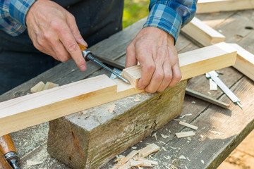 a senior carpenter working with wood outdoors during sunny day