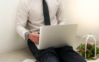 A business man sitting on the ground playing computer