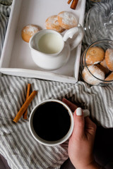 hand with a cup of coffee cozy flat lay in scandinavian style. Coffee with cookies in bed.