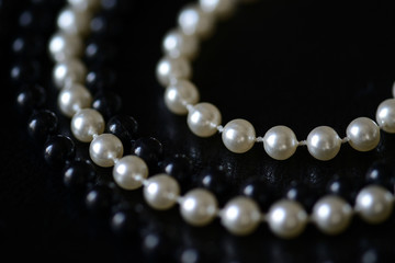 Fragment of a necklace of black and white beads on a black background close-up. Fashion background