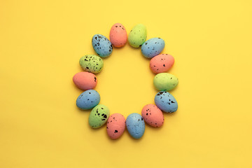 Obraz premium Colorful easter eggs painted in pastel colors on yellow background. Easter greeting card concept in trendy minimal style, copy space
