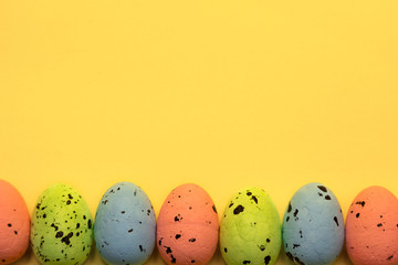Colorful easter eggs painted in pastel colors in row on yellow background. Easter greeting card concept in trendy minimal style, copy space