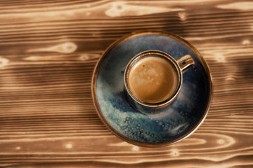 Top view of classic blue color cup of espresso on wooden background