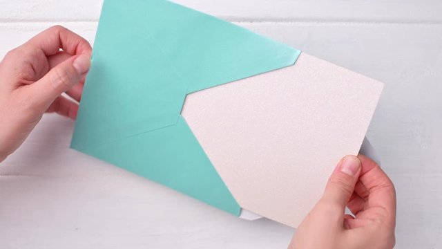 Female hands open the envelope and take out a sheet.