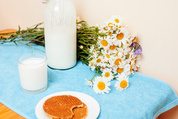 Simply stylish wooden kitchen with bottle of milk and glass on table, summer flowers camomile, healthy foog moring concept