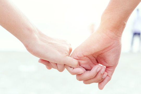 close up hands of lovely couple hooking each other's little finger together with copy space for text and soft light.