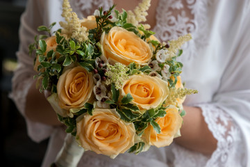 wedding bouquet with tea roses in the hands of the bride in white lace peignoir