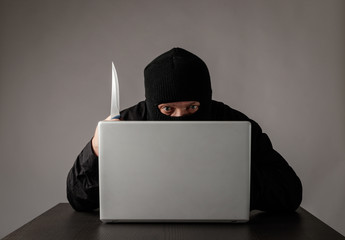 Hacker in mask using a laptop.