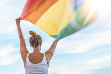 Woman Waving Rainbow Flag at Gay Parade. Young woman with a rainbow flag. Lesbian Girl Holding LGBT Flag. Female is holding the gay rainbow flag