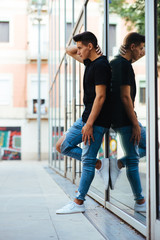 Young man leaning on a window pane.