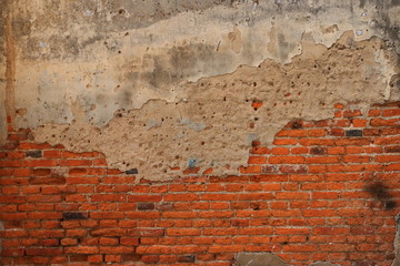 Vintage weathered brick wall with cement plaster finish, part of cement is cracked