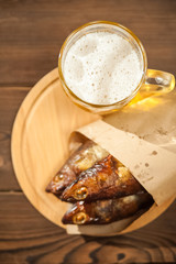 Beer glass with beer and hot smoked fish close-up. Beer mug with beer and fish on a dark background and copy space.