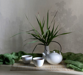White chinese teapot and cups with tea on table close-up