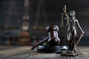 Justice concept. Themis statue and judge's gavel on the rustic wooden table and the dark background. - obrazy, fototapety, plakaty