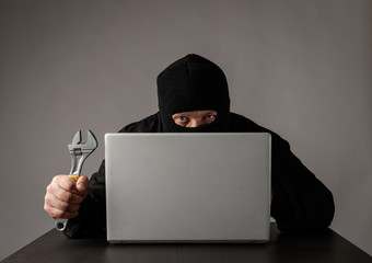 Hacker in mask using a laptop.