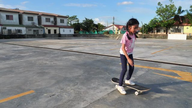 Slow motion little Asian girl playing skateboard with happiness