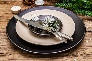Christmas and New Year dinner place setting. Evergreen fir tree branch, candles, cones, ceramic...