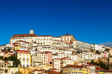 Fototapeta na wymiar View of the high of Coimbra, Portugal, with its old houses up the hill to the University Tower on a sunny day with blue sky.