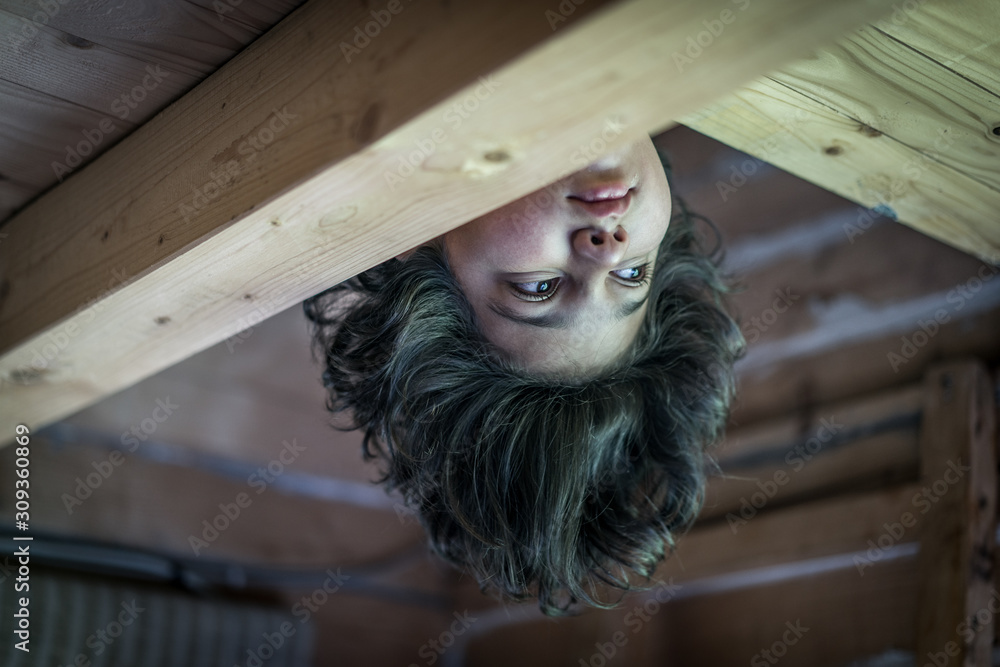 Wall mural Upside down boy in wooden cottage