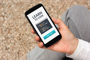 Hand holding smart phone with learn to code concept on screen