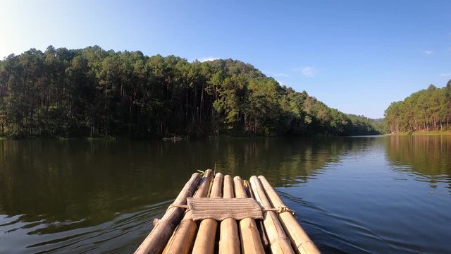 Sailing the bamboo boat in the  big river against a natural tree and forest