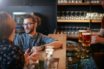 Smiling caucasian couple sitting near bar counter, chatting and waiting for beer.