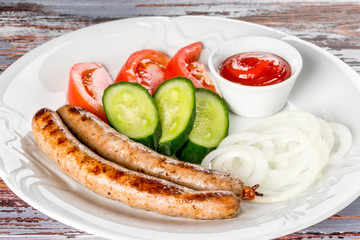 Sausages with vegetables on a white plate on a background