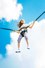 Little girl bouncing high in the air using a bungee trampoline.