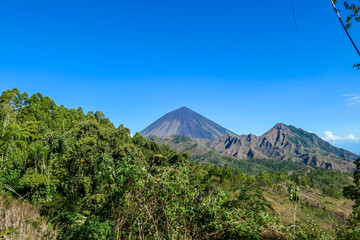 A distant view on Volcano Inierie, Bajawa, Indonesia. The pyramid like mountain towers above the landline. There are no other high volcanos around. The upper slopes are bare without any vegetation.