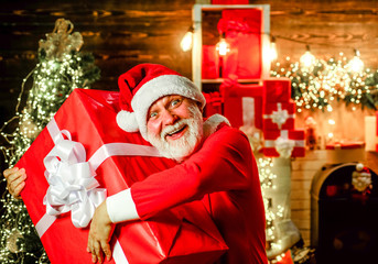 Fototapeta na wymiar Christmas and new year concept. Bearded man in Santa hat holds Christmas present. Present box. Santa Claus man holds christmas gift box. Christmas, winter, happiness, presents. New Year holidays.