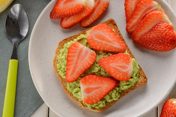 Toast with mashed avocado and sliced strawberry