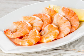 Cooked shrimp on a white plate with lemon