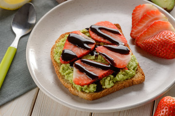 Toast with avocado and strawberry poured with chocolate syrup
