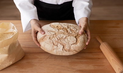 Crop baker holding bread over table