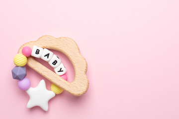 Baby wooden toy and teethers pastel colors on pink background