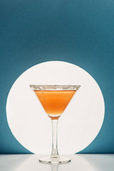 fresh cocktail in martini glass on blue background with back light