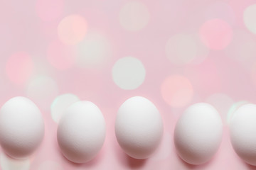 White eggs on a pastel pink background with bokeh lights - Easter festive backdrop