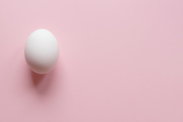 One whitEaster egg on a pastel pink background with copy space