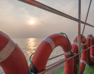 Lifebuoys aboard a pleasure craft against the morning sun and its reflection in the calm ocean...