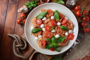Italian Colorful Pasta dish or Spaghetti Napolitana with cherry tomatoes, vegan mozzarella and basil 