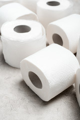close up view of rolls of toilet paper on grey textured surface