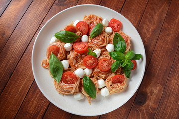 Italian Colorful Pasta dish or Spaghetti Napolitana with cherry tomatoes, vegan mozzarella and basil 