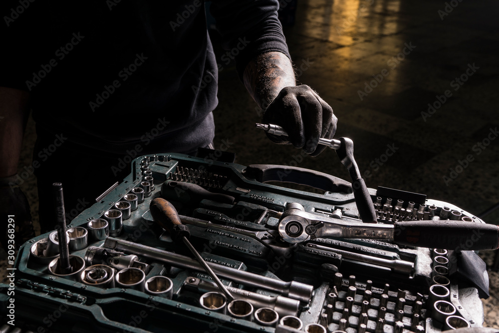 Wall mural detail of the hands of a mechanic taking a screwdriver from a toolbox