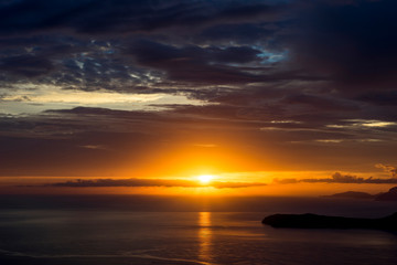 Naklejka na ściany i meble Sunset on a cloudy day in the sea near the coast