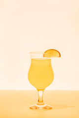 yellow cocktail with citrus slice on bright background