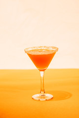orange cocktail in martini glass with sugar on bright background