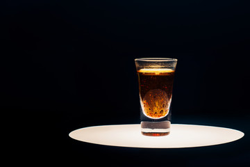 alcohol shot on illuminated circle isolated on black