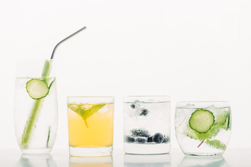 refreshing drinks with blueberries, celery, straw, mint, cucumber and ice isolated on white