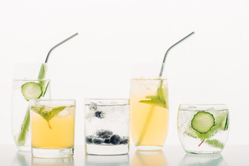 refreshing drinks with blueberries, celery, straws, mint, cucumber and ice isolated on white